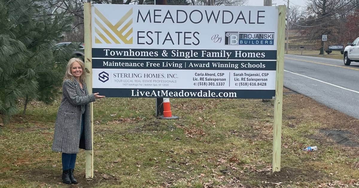 woman standing by meadowdale estates sign