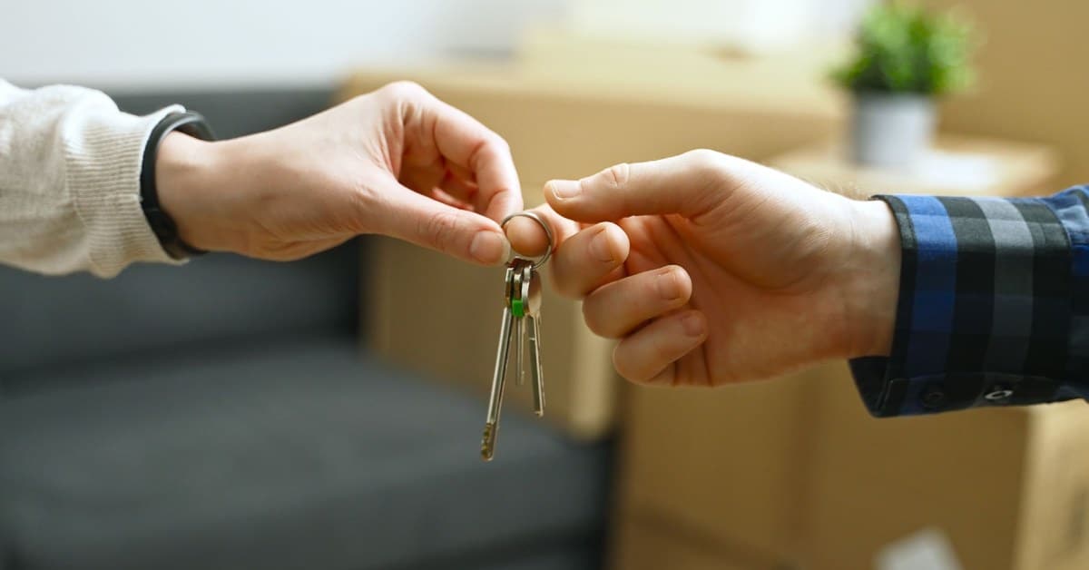 person handing keys to another person in a house